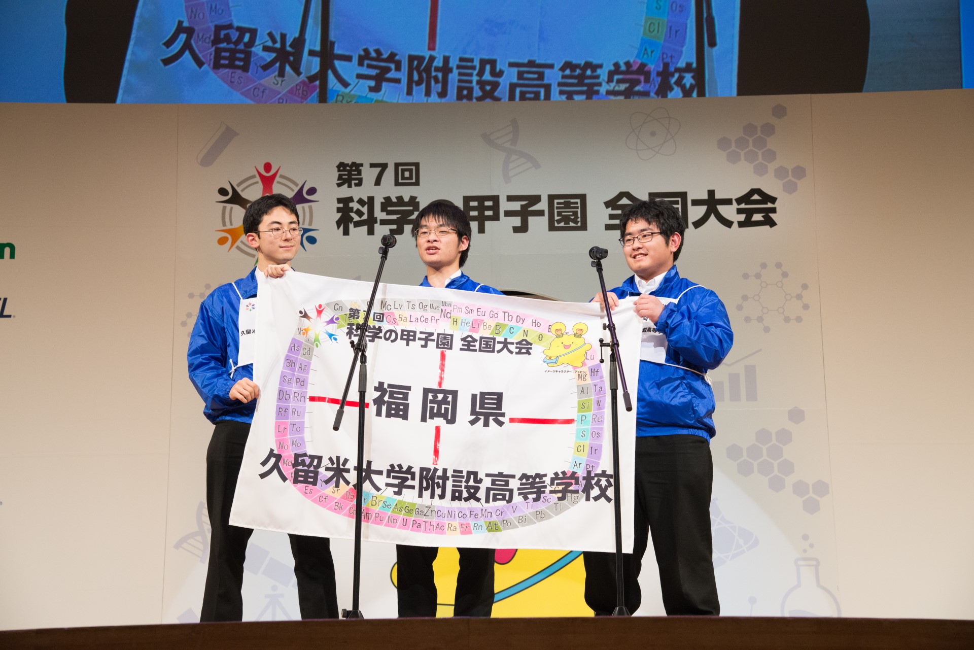 県代表旗を持ってステージに立つ男子高校生３人